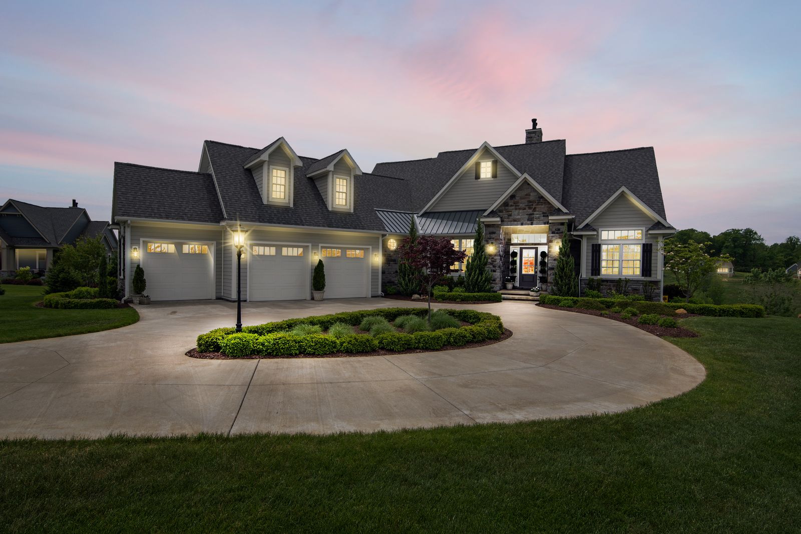 Modern two-story home lit up at dusk with large windows